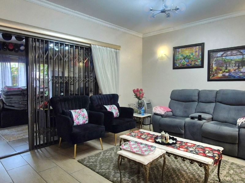 A comfortable living room featuring tiled flooring, wall sconces, and a sliding glass door with a security gate leading to an outdoor area.