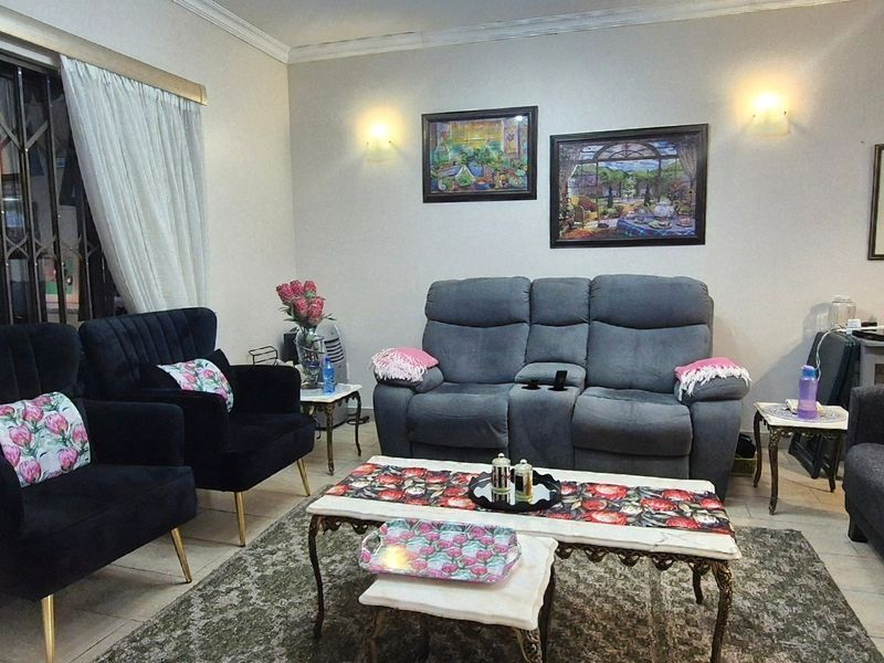 A comfortable living room featuring neutral walls, decorative coving, wall sconces, and a security gate over the window.