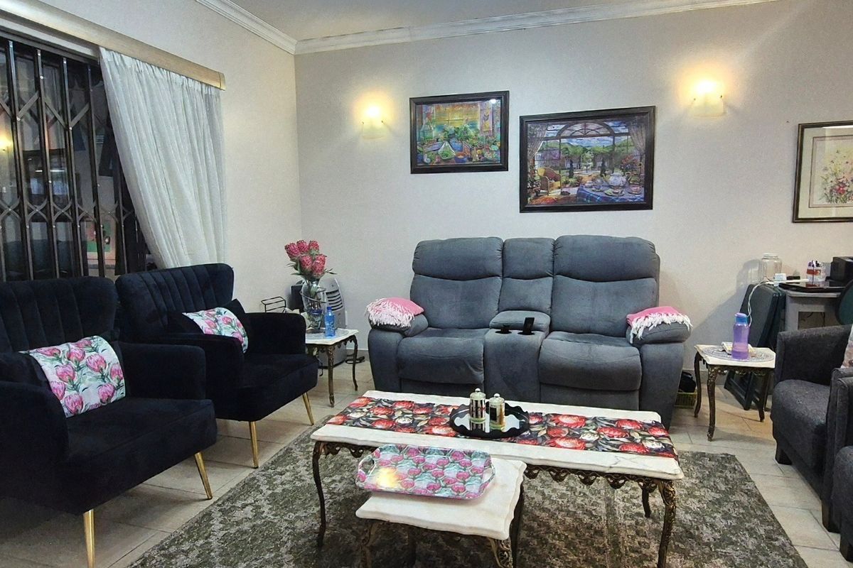 A comfortable living room featuring neutral walls, decorative coving, wall sconces, and a security gate over the window.