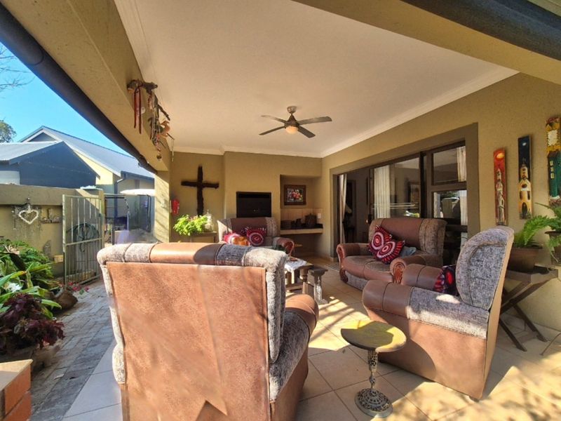 A covered outdoor patio featuring tiled flooring, a built-in braai, and ceiling fan, providing a comfortable space for outdoor entertaining.