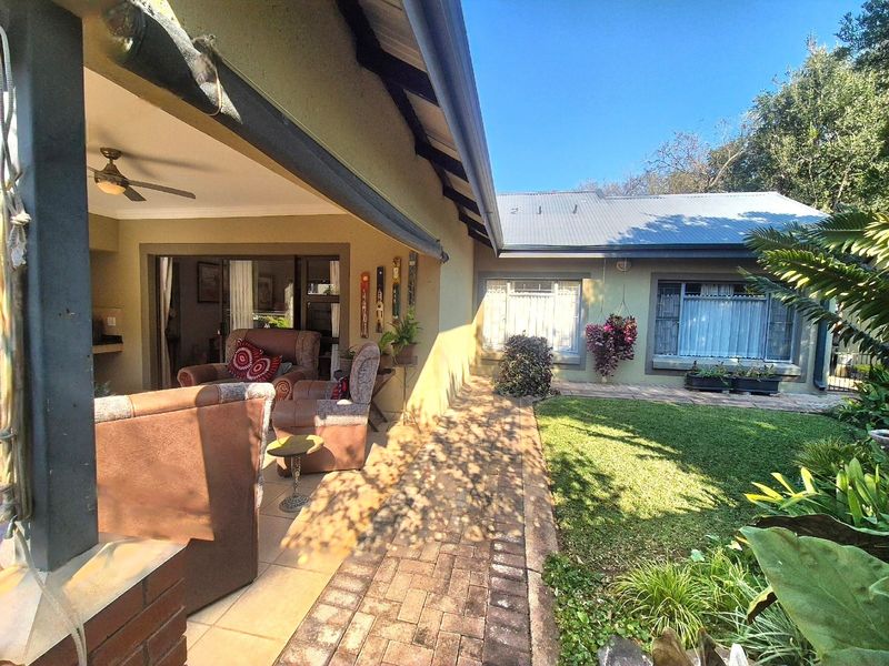 A covered patio area featuring brick paving and a ceiling fan, providing seamless access to the interior living space through sliding glass doors.