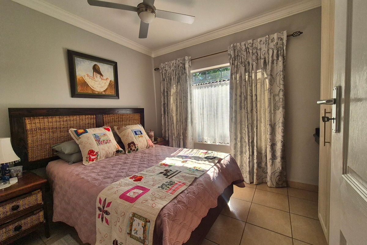 A comfortable bedroom featuring tiled flooring, a ceiling fan, and built-in storage, offering a functional and well-maintained living space.