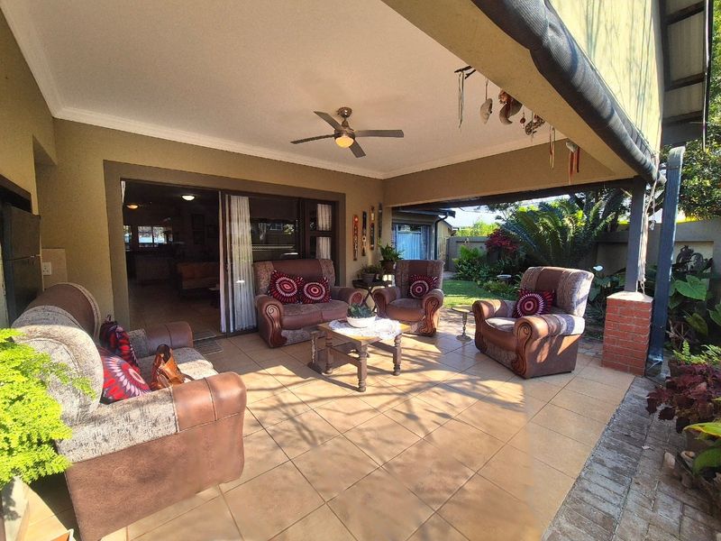 A covered outdoor patio featuring tiled flooring, a ceiling fan, and direct access to the interior living space through sliding glass doors.