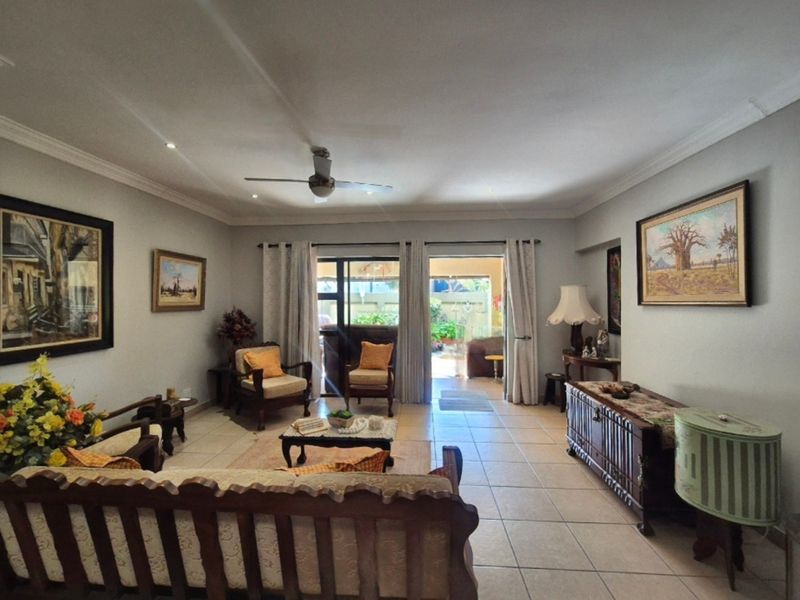 Spacious living room featuring tiled flooring, recessed lighting, a ceiling fan, and sliding glass doors providing access to the outdoor patio area.