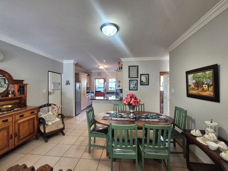 Open plan dining area flowing into a functional kitchen with granite countertops and tiled flooring throughout.