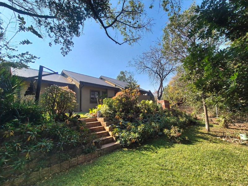 Rear view of the house featuring a landscaped garden, brick retaining walls, and a staircase leading up to the property.