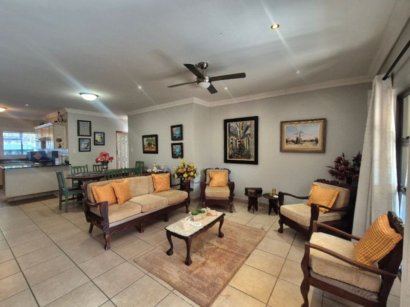 Spacious open-plan living and dining area featuring ceramic floor tiles, recessed lighting, and a ceiling fan, seamlessly connected to a functional kitchen space.