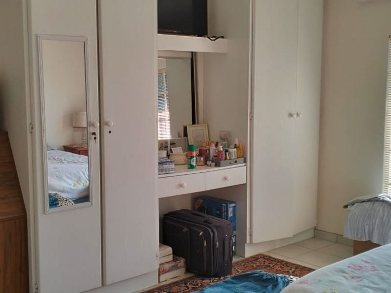 A bedroom featuring built-in cupboards with an integrated vanity unit and window blinds.
