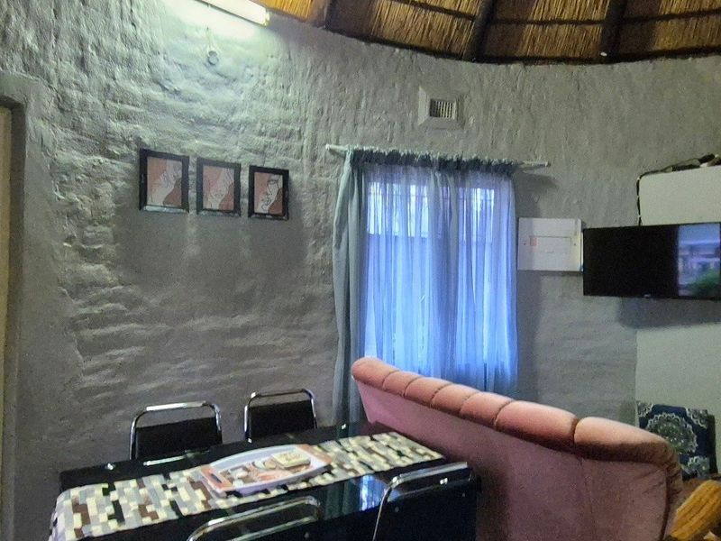Living area featuring a traditional thatched roof and textured brick walls, offering a rustic aesthetic with potential for modernization.