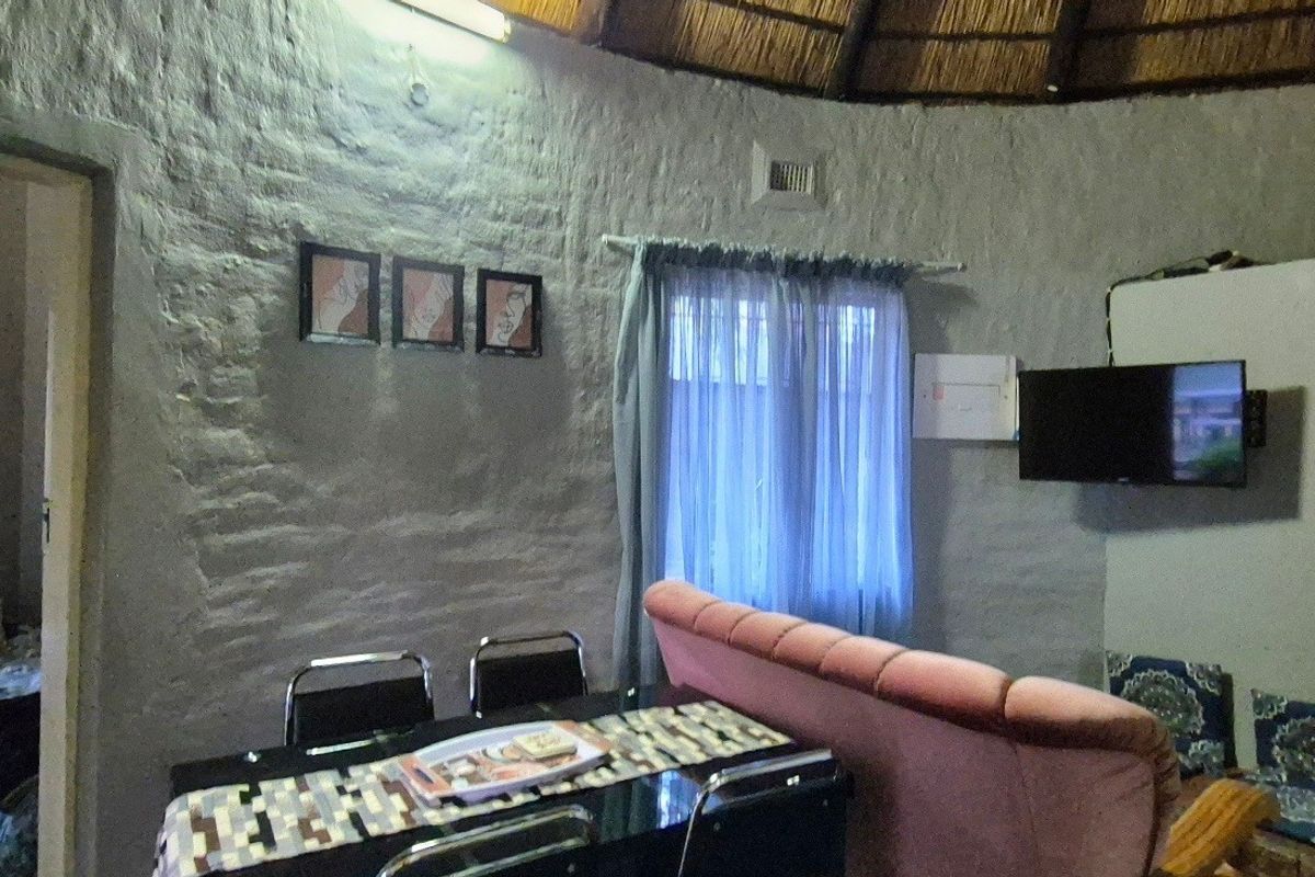 Living area featuring a traditional thatched roof and textured brick walls, offering a rustic aesthetic with potential for modernization.