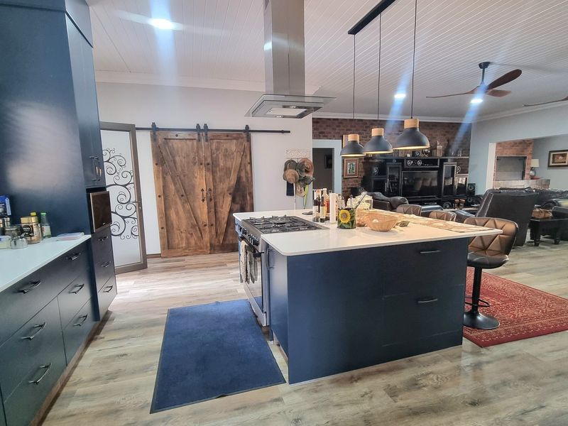 Spacious open-plan kitchen and living area featuring a central island with gas hob, modern cabinetry, and rustic sliding barn doors.