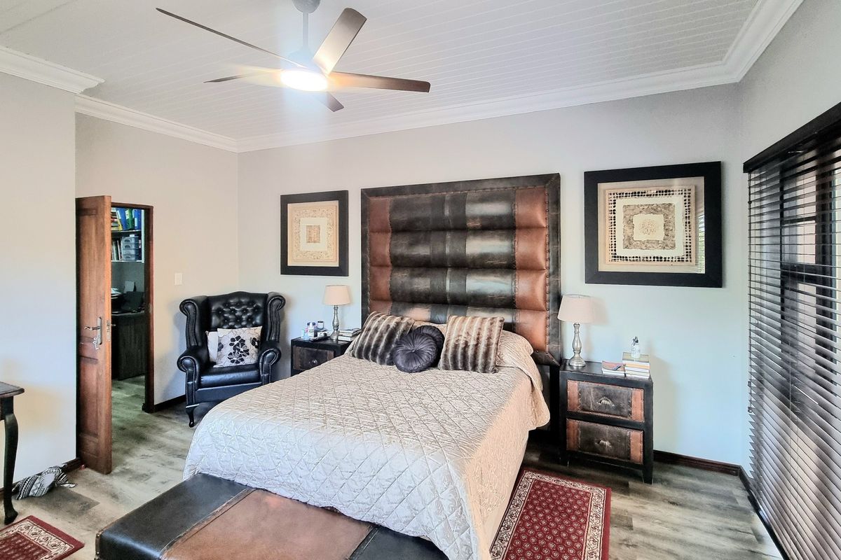 A well-maintained bedroom featuring laminate flooring, a ceiling fan, and tongue and groove ceiling detail with crown molding.