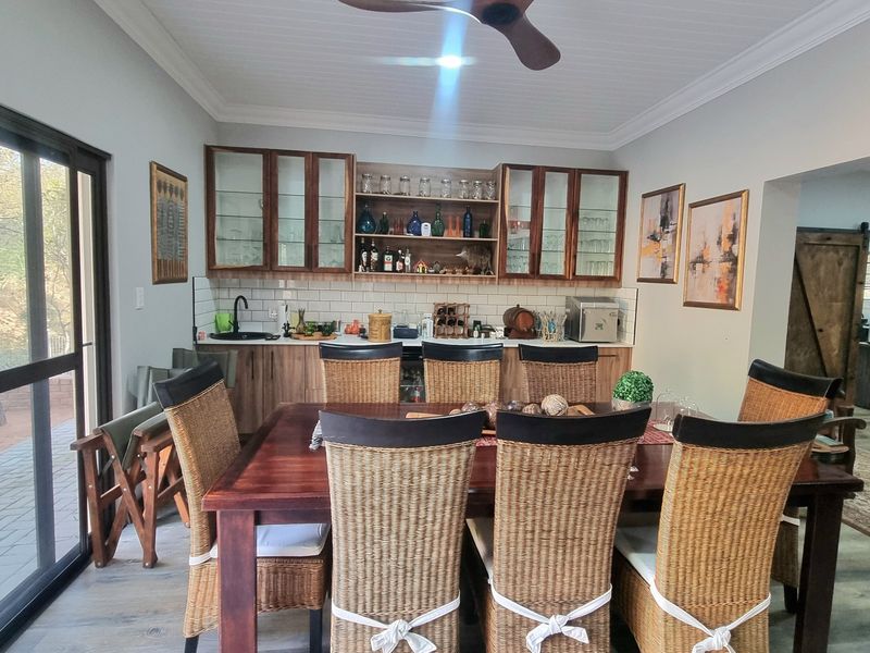 A well-appointed home bar area featuring custom cabinetry, subway tile backsplash, and an integrated sink, seamlessly connected to an outdoor patio space.