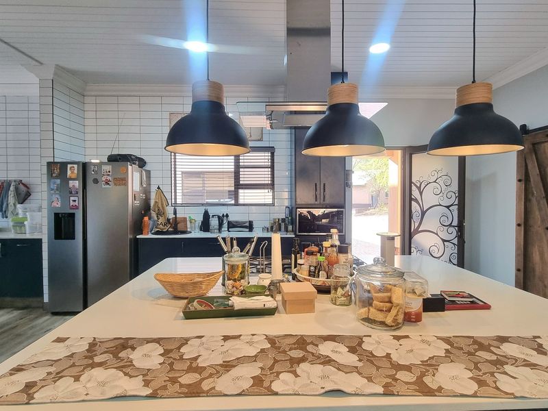Modern kitchen featuring a large central island, pendant lighting, subway tile backsplash, and a distinctive barn door, creating a functional and stylish culinary space.