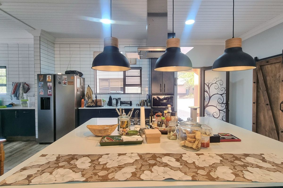 Modern kitchen featuring a large central island, pendant lighting, subway tile backsplash, and a distinctive barn door, creating a functional and stylish culinary space.