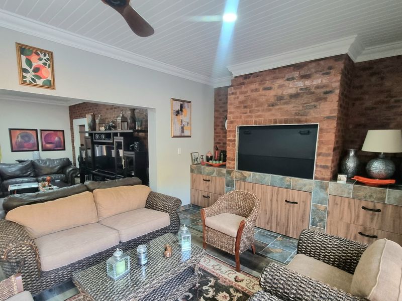 Spacious living room featuring a prominent brick fireplace, built-in cabinetry, ceiling fan, and tiled flooring, creating a warm and inviting atmosphere.