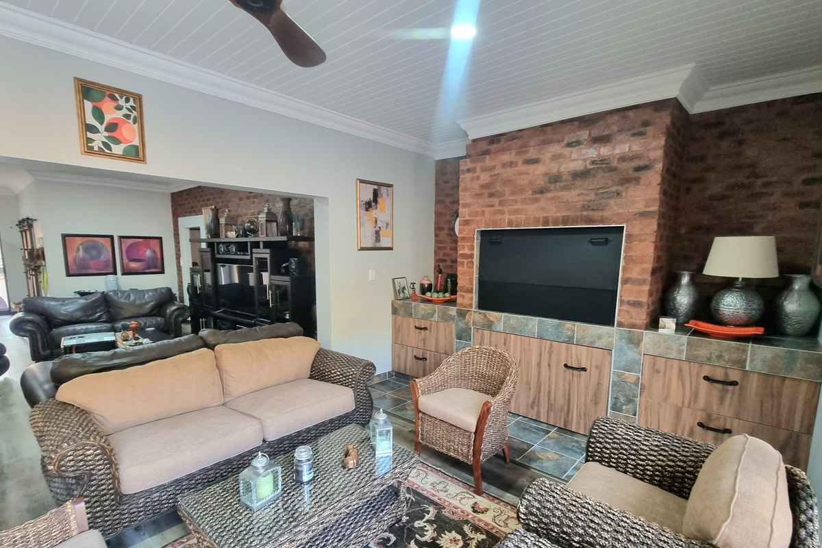 Spacious living room featuring a prominent brick fireplace, built-in cabinetry, ceiling fan, and tiled flooring, creating a warm and inviting atmosphere.