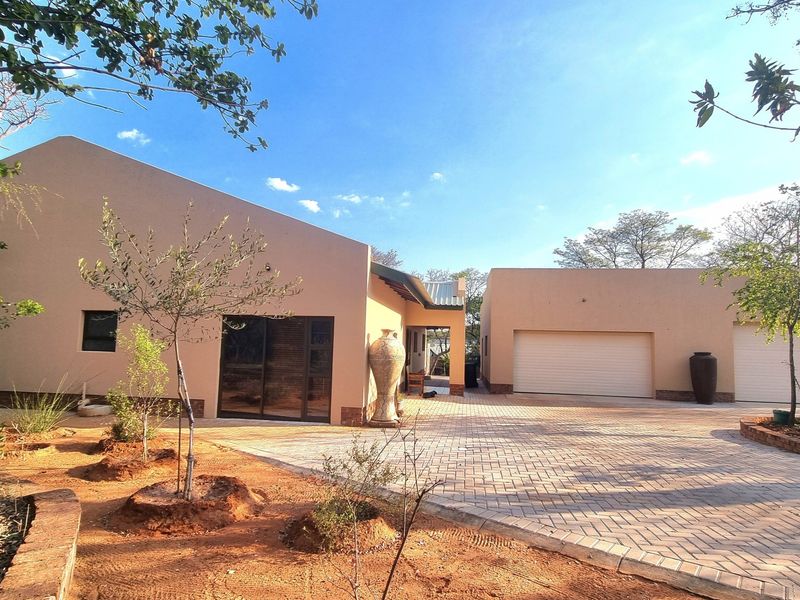 Front view of a modern house featuring a paved driveway, double garage, and clean exterior finishes set in a landscaped garden.