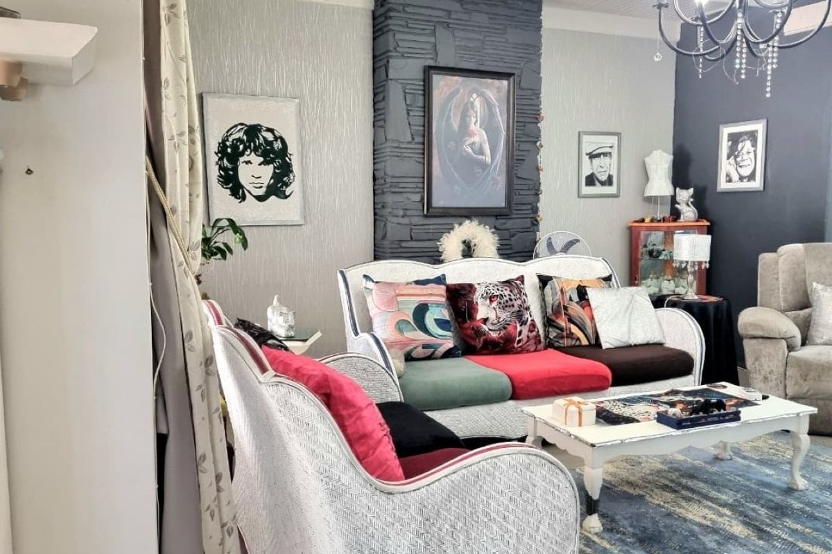 A living room featuring a prominent stone-clad fireplace feature wall, textured wallpaper, and a decorative chandelier.