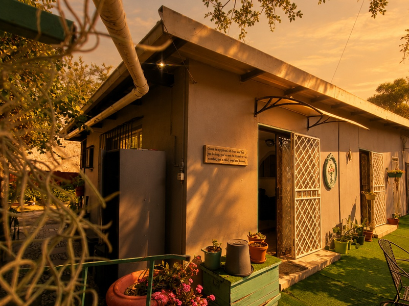 A view of the rear exterior of the house featuring a security gate, awning, and established garden area.