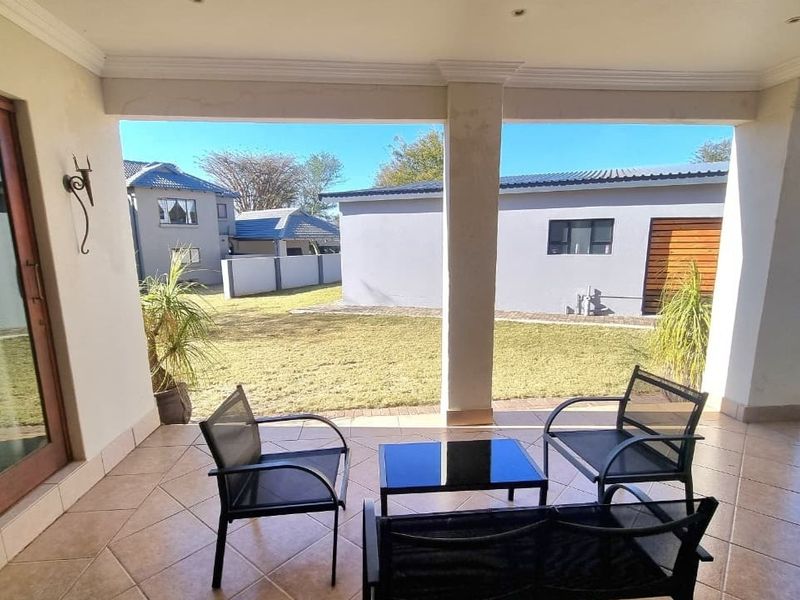 A covered patio featuring tiled flooring, recessed lighting, and direct access to the rear garden through a large sliding glass door.