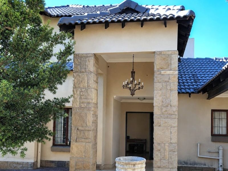 Front entrance featuring stone-clad pillars, a tiled roof, and a decorative hanging chandelier, providing a welcoming architectural facade.