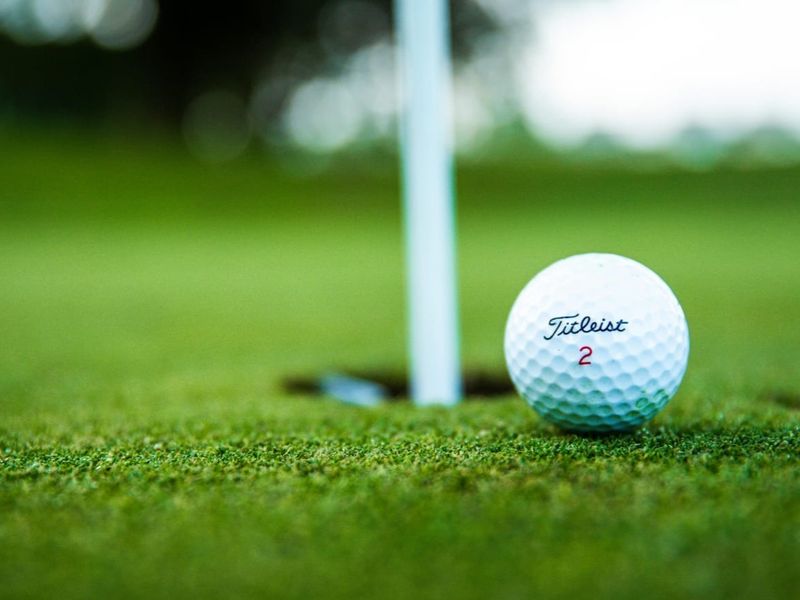 A close-up view of a golf ball on a putting green next to a flagstick.