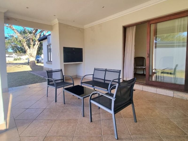 Covered patio area featuring tiled flooring, a built-in braai, and sliding glass door access to the interior living space.