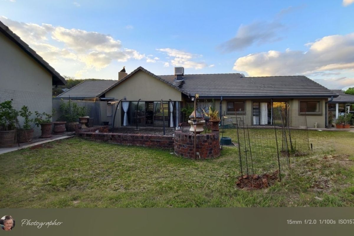 Rear view of the property featuring a brick patio, tiled roof, and sliding glass doors leading to the garden area.