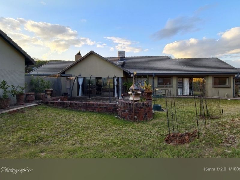 Rear view of the property featuring a brick patio, tiled roof, and sliding glass doors leading to the garden area.