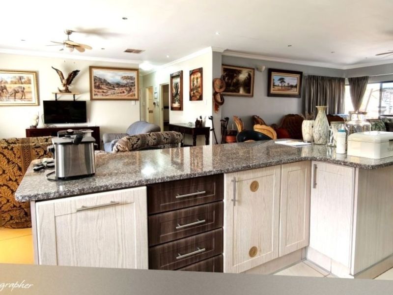An open-plan living and kitchen area featuring granite countertops, two-tone cabinetry, and ceiling fans, creating a functional and connected family space.