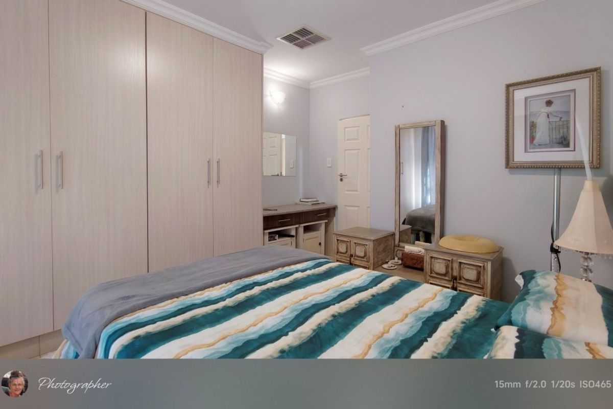 A well-maintained bedroom featuring extensive built-in cupboards, cove cornicing, and integrated air conditioning ventilation.