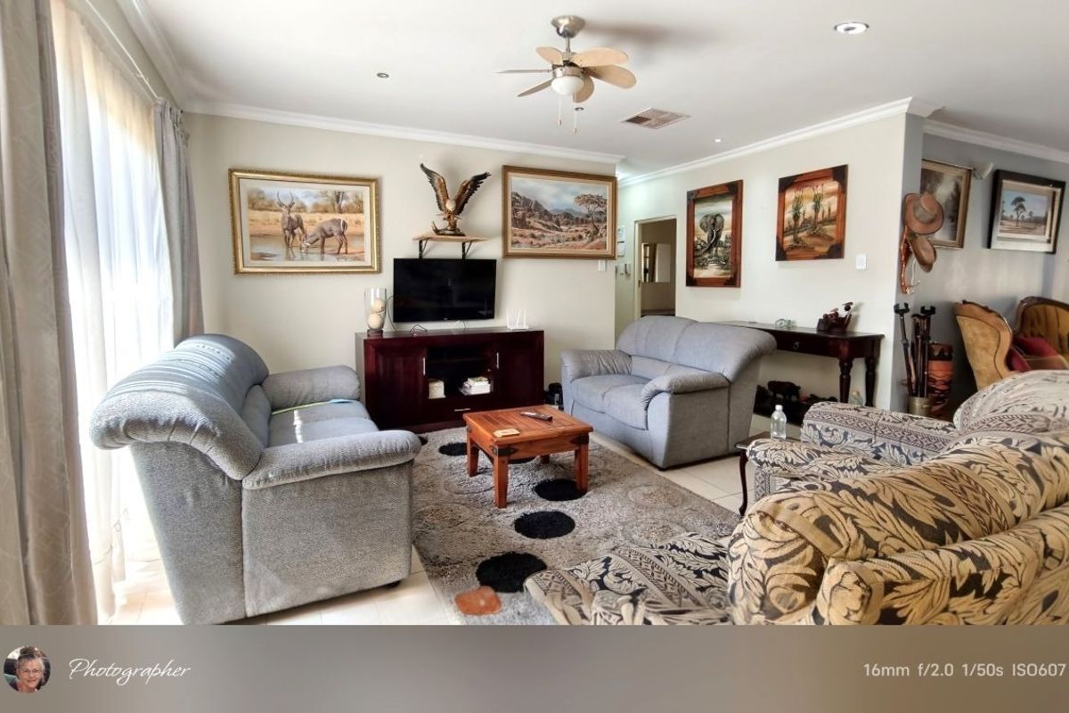 A comfortable living room featuring tiled flooring, recessed lighting, a ceiling fan, and a sliding glass door providing natural light.