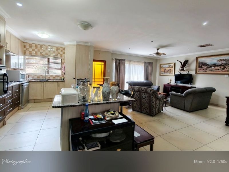 Spacious open-plan living area featuring a functional kitchen with granite countertops, built-in cabinetry, and tiled flooring throughout the combined lounge and dining space.