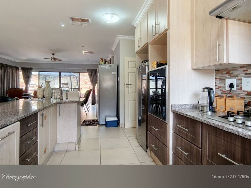 Open-plan kitchen and living area featuring granite countertops, built-in oven, gas hob, and tiled flooring, creating a functional and connected living space.