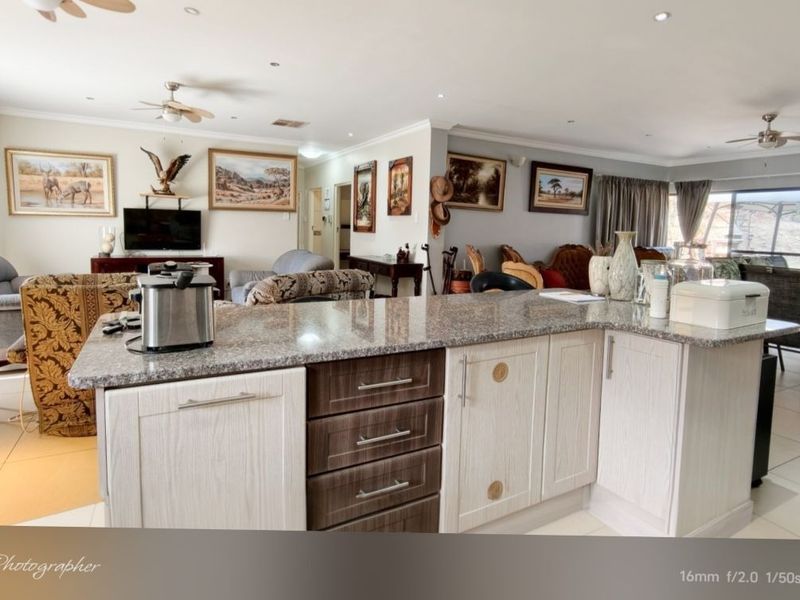 Spacious open-plan living area featuring a central kitchen island with granite countertops, integrated cabinetry, and seamless flow to the adjacent lounge and patio.
