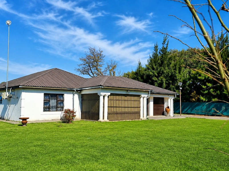 A view of the rear exterior of the house featuring a tiled roof, covered patio area with columns, and a spacious lawn.