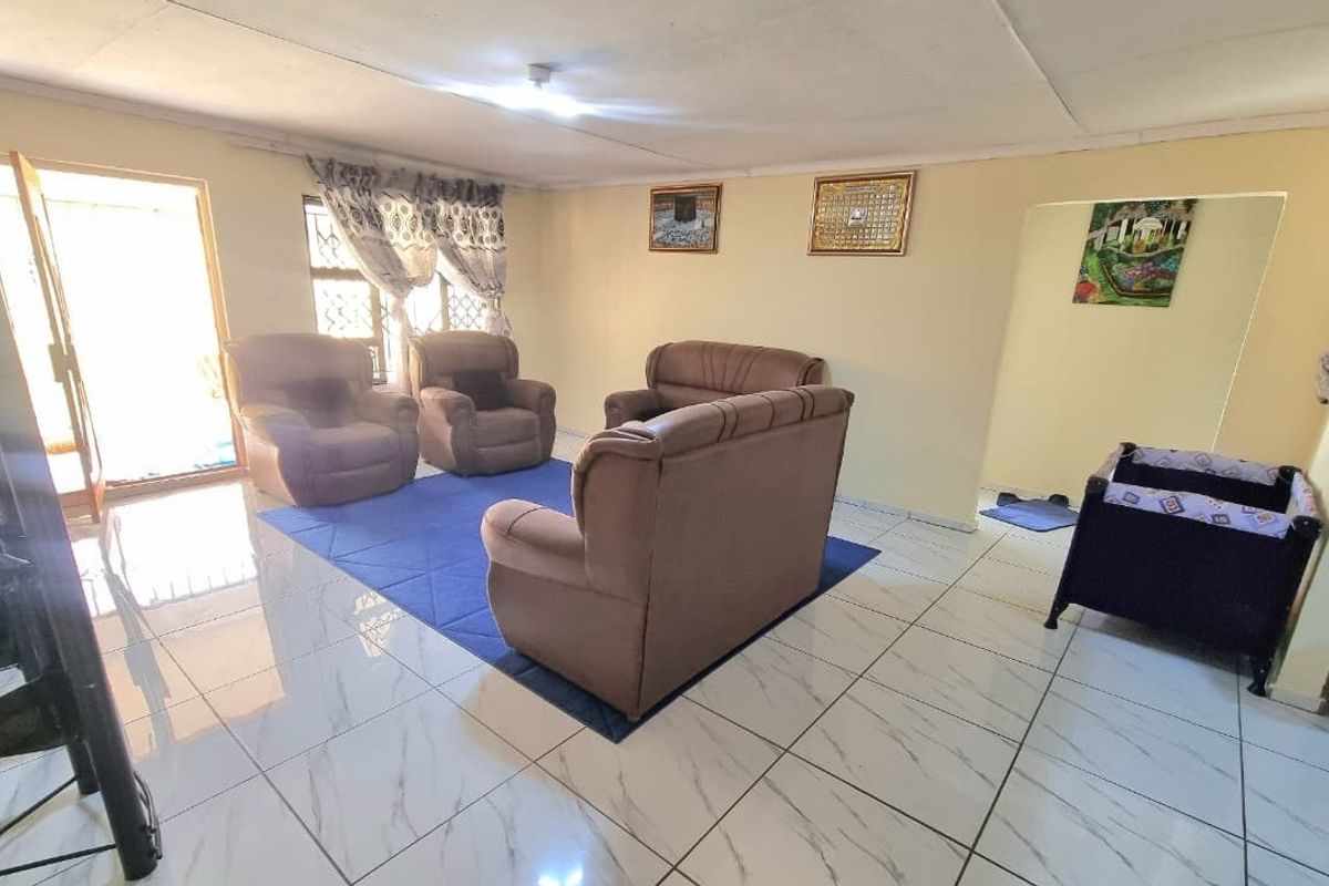 A living room featuring white marble-look tiled flooring and a sliding glass door providing access to the exterior.