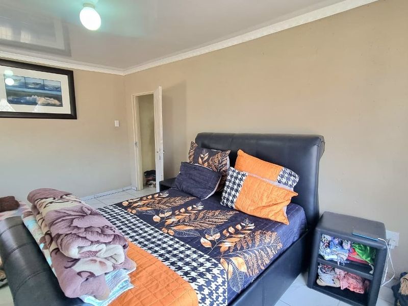 A standard bedroom featuring tiled flooring and coved ceiling details, providing a functional living space.