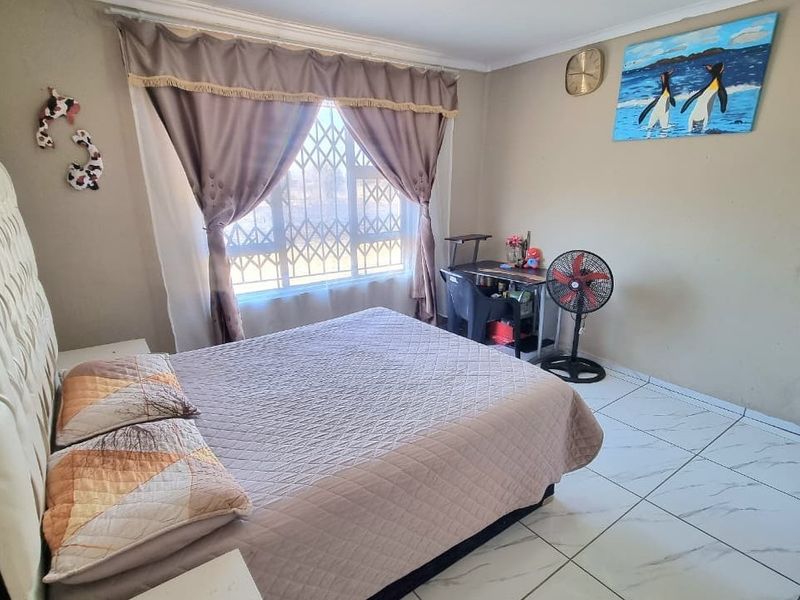 A standard bedroom featuring tiled flooring and a window fitted with a security gate.