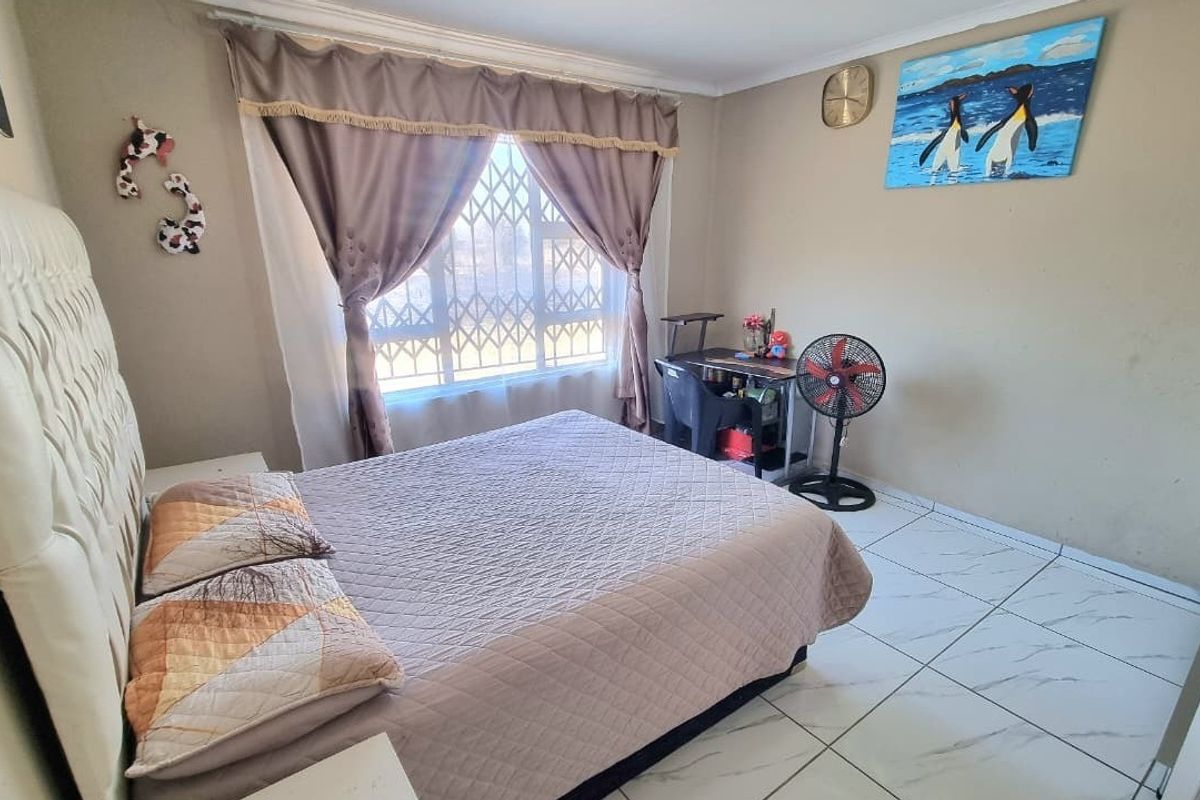 A standard bedroom featuring tiled flooring and a window fitted with a security gate.