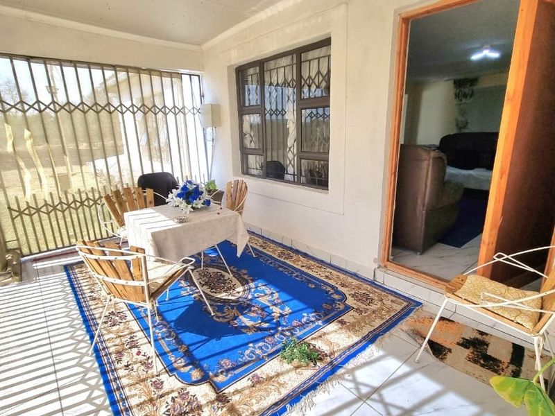 A covered patio area featuring tiled flooring and security bars, providing a transition space between the outdoor area and the interior living room.
