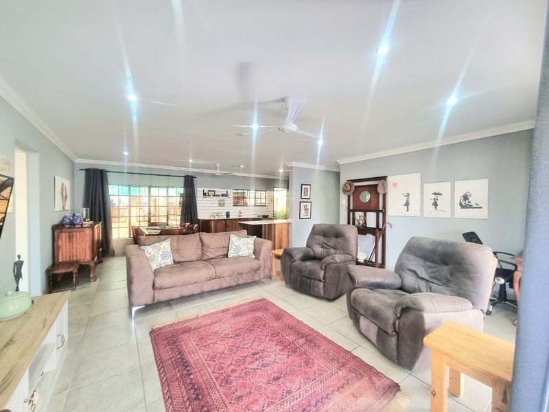 Spacious open-plan living area featuring tiled flooring, recessed lighting, ceiling fans, and a functional kitchen with a central island.