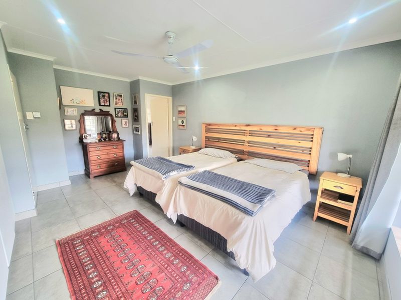 A spacious bedroom featuring neutral wall tones, tiled flooring, a ceiling fan, and recessed lighting, providing a comfortable and functional living space.