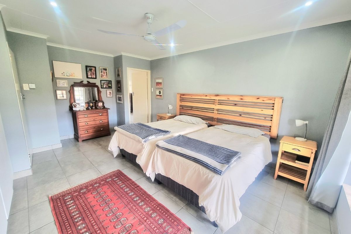 A spacious bedroom featuring neutral wall tones, tiled flooring, a ceiling fan, and recessed lighting, providing a comfortable and functional living space.