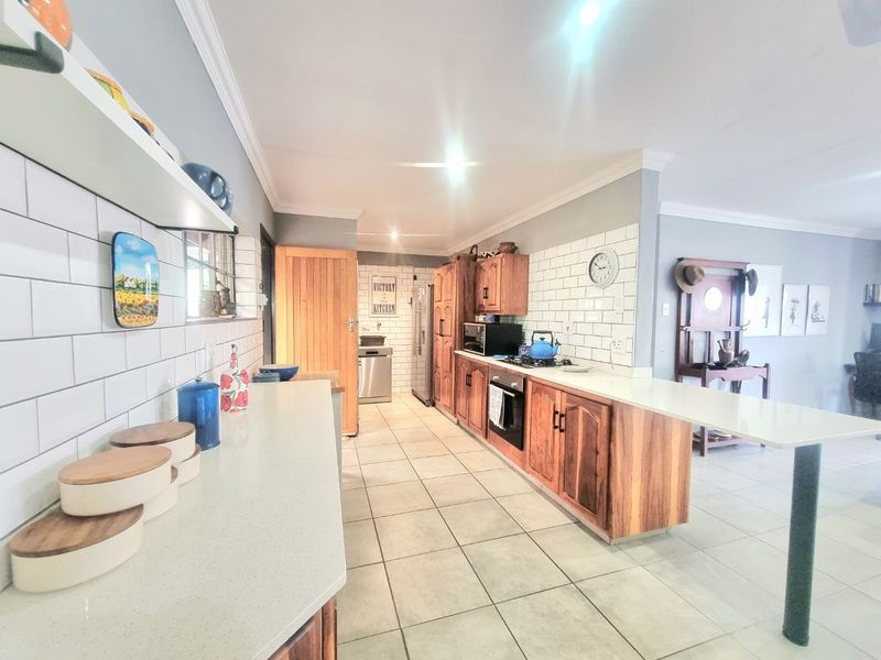 A well-maintained kitchen featuring wooden cabinetry, subway tile backsplash, stone countertops, and a breakfast bar, offering a functional and classic design.