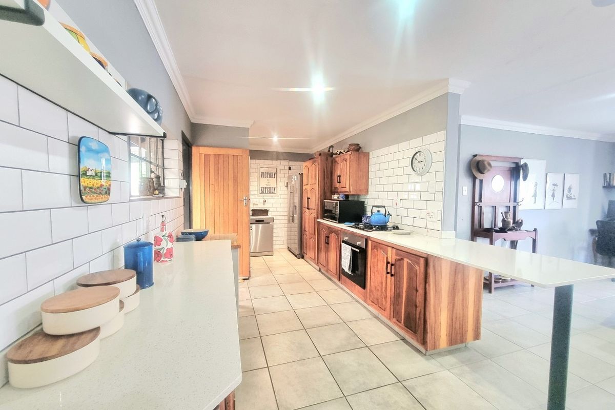 A well-maintained kitchen featuring wooden cabinetry, subway tile backsplash, stone countertops, and a breakfast bar, offering a functional and classic design.