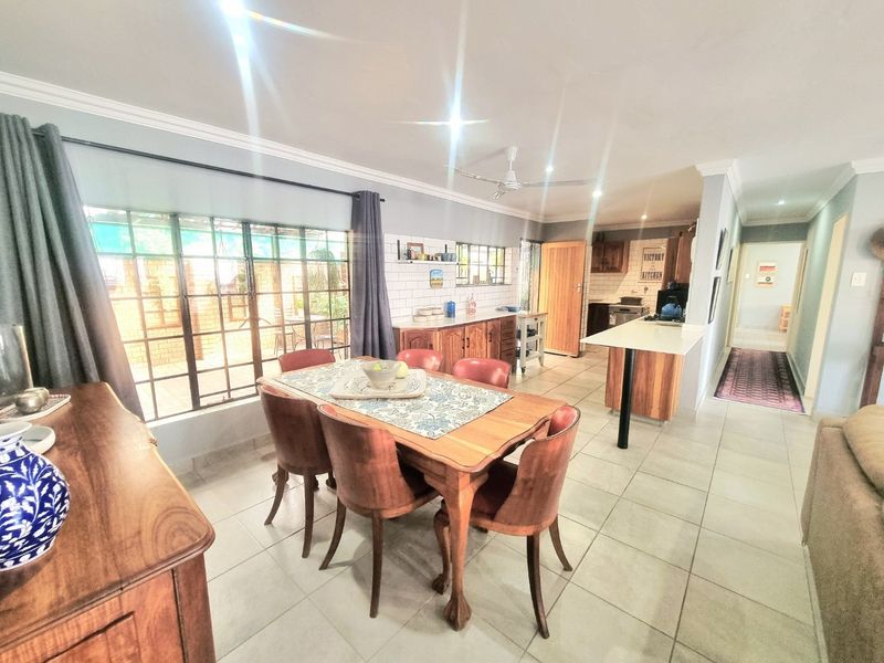 Open plan dining and kitchen area featuring tiled flooring, a breakfast bar, and subway tile backsplash, providing a functional and connected living space.