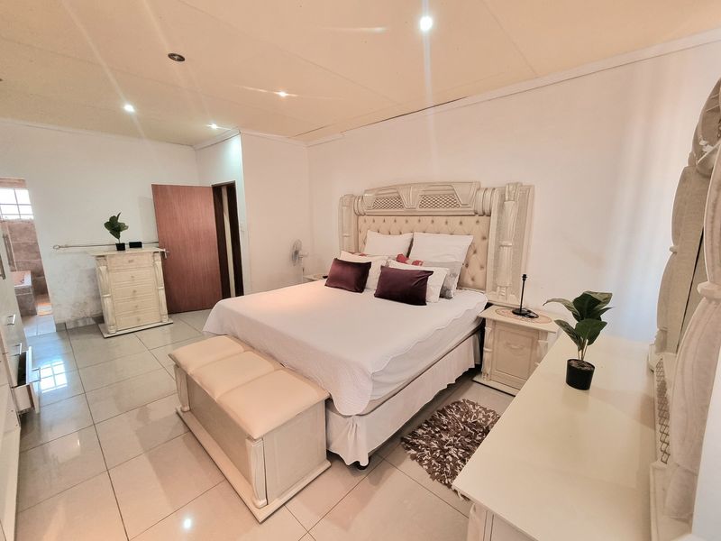 Spacious bedroom featuring tiled flooring, recessed downlighting, and direct access to an en-suite bathroom.