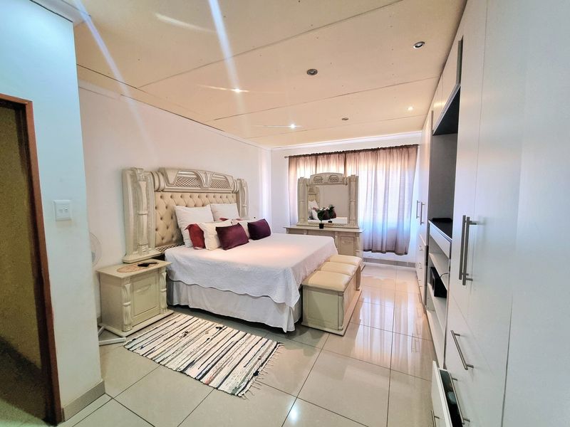 Spacious bedroom featuring tiled flooring, recessed ceiling lighting, and extensive built-in cupboard storage.